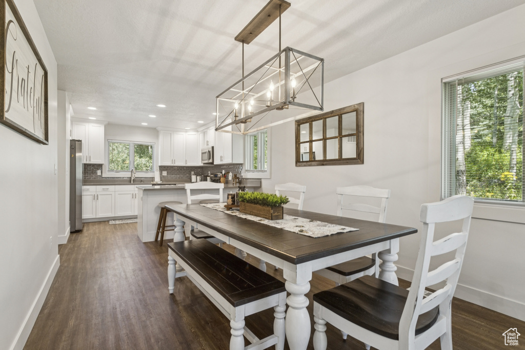 Dining room with a chandelier, dark wood finished floors, and recessed lighting
