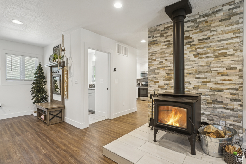 Living area featuring a wood stove, wood finished floors, recessed lighting, and a textured ceiling
