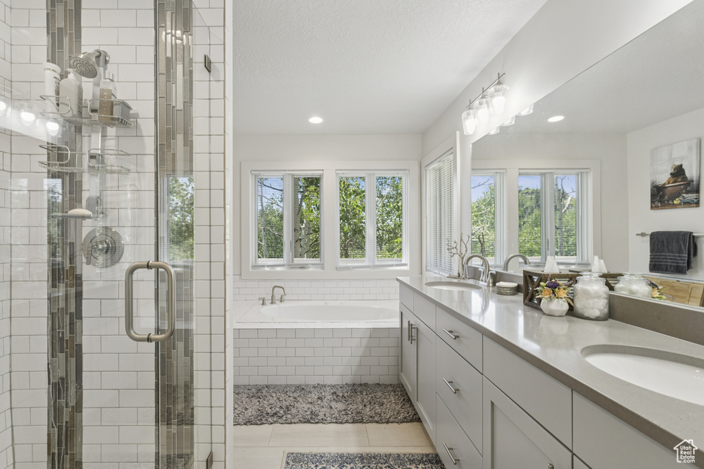 Full bath with healthy amount of natural light, double vanity, a bath, a stall shower, and recessed lighting