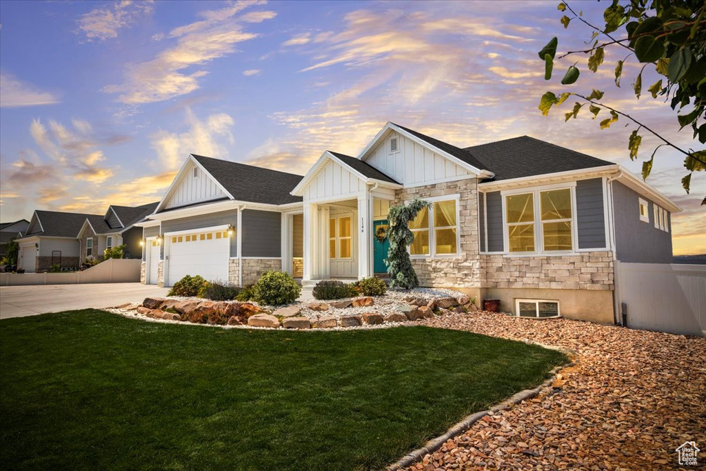 View of front facade featuring stone siding, board and batten siding, concrete driveway, and an attached garage