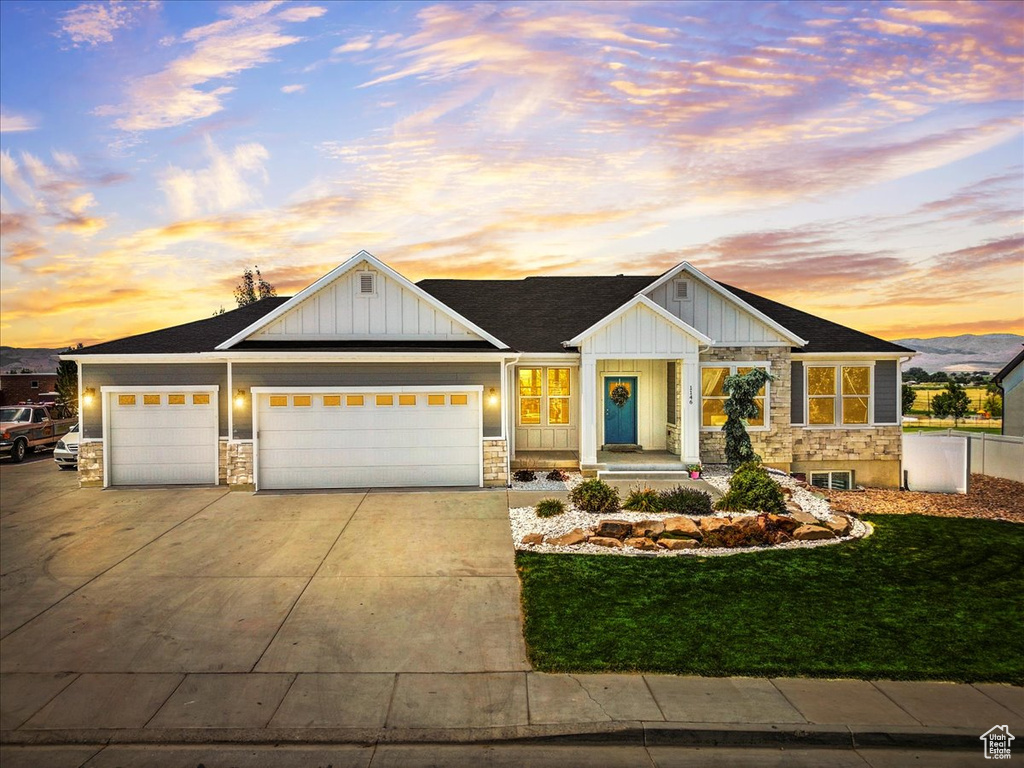 View of front of property featuring stone siding, board and batten siding, concrete driveway, and a garage
