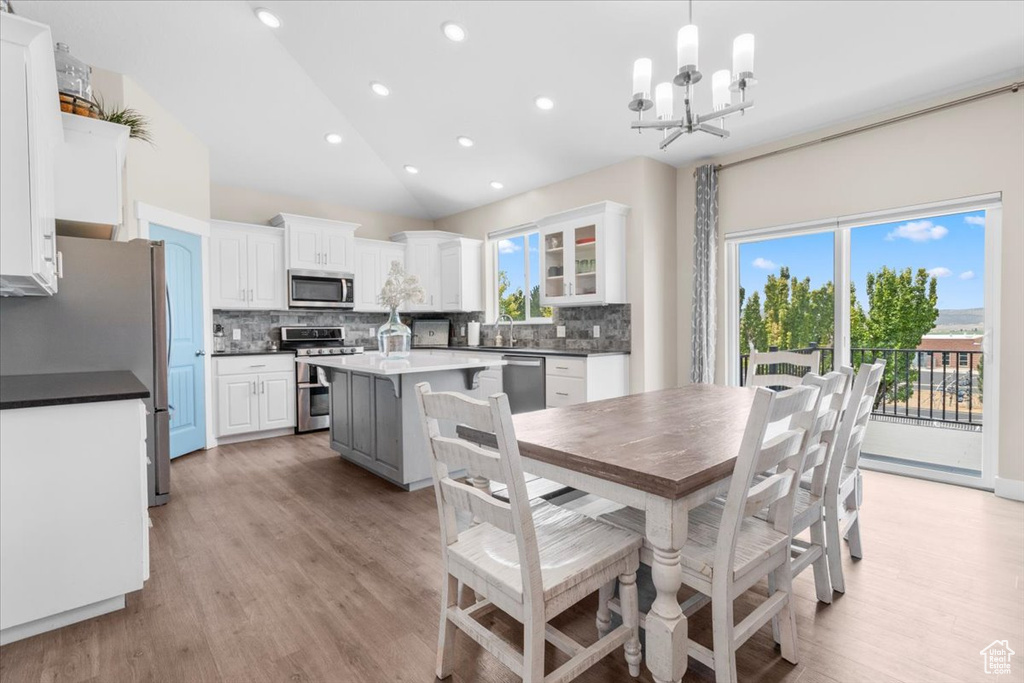 Dining room featuring a chandelier, vaulted ceiling, healthy amount of natural light, light wood-type flooring, and recessed lighting