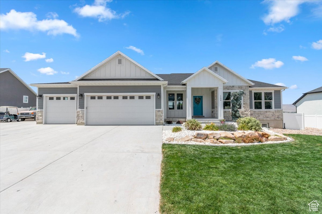 View of front of home featuring stone siding, an attached garage, board and batten siding, and concrete driveway