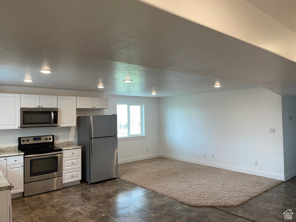 Kitchen featuring stainless steel appliances, white cabinetry, and a textured ceiling