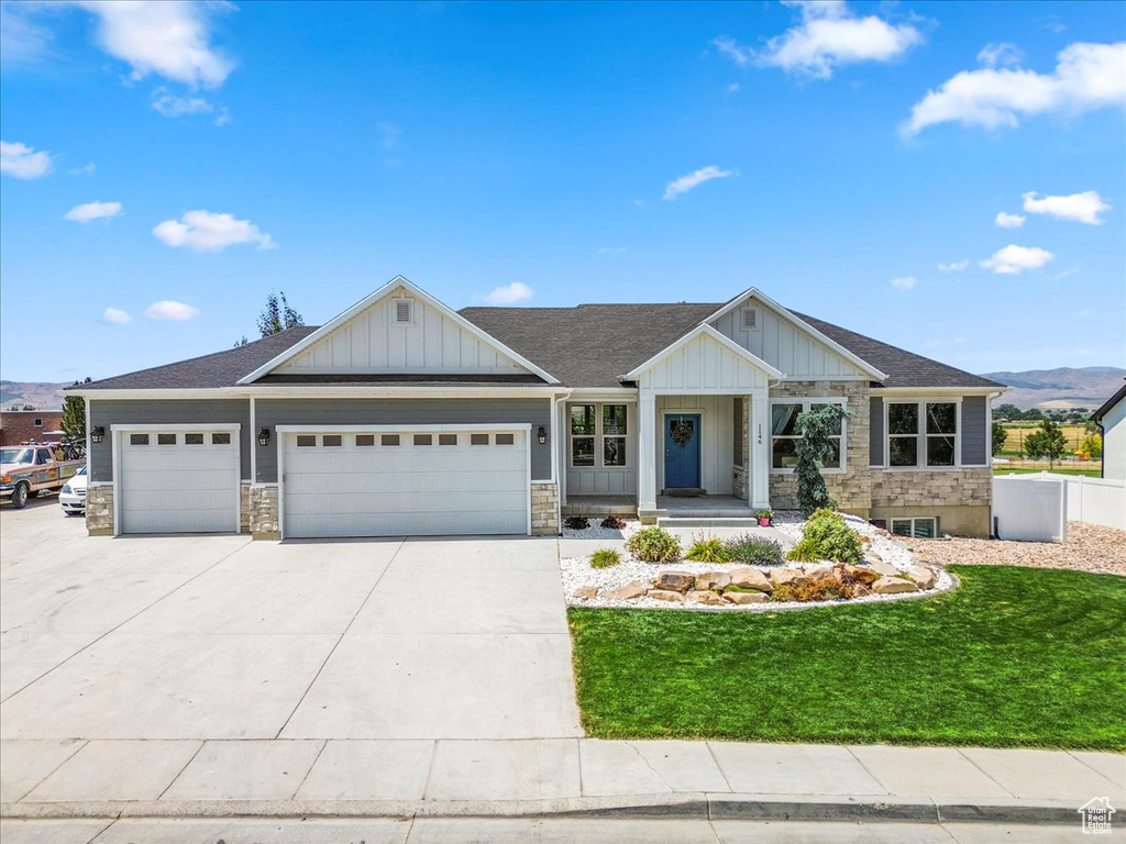 View of front of house with an attached garage, stone siding, board and batten siding, and driveway
