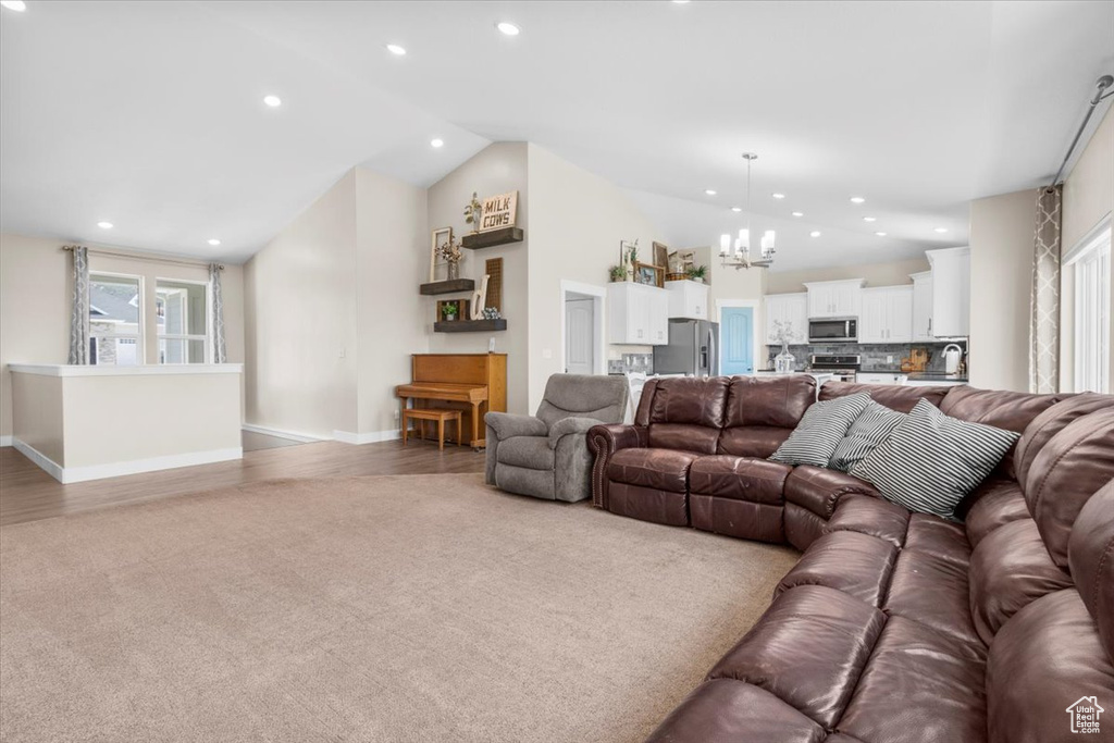 Living room with vaulted ceiling, a chandelier, recessed lighting, and light wood-style floors