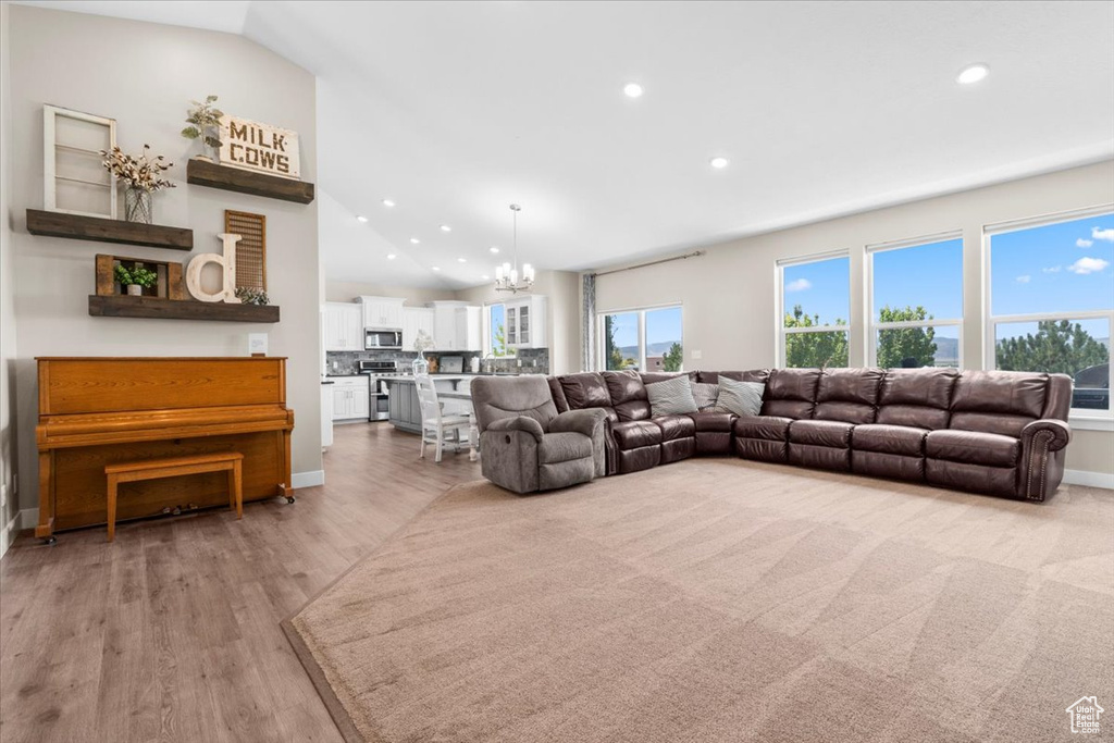 Living area with a chandelier, recessed lighting, light wood-style floors, and vaulted ceiling
