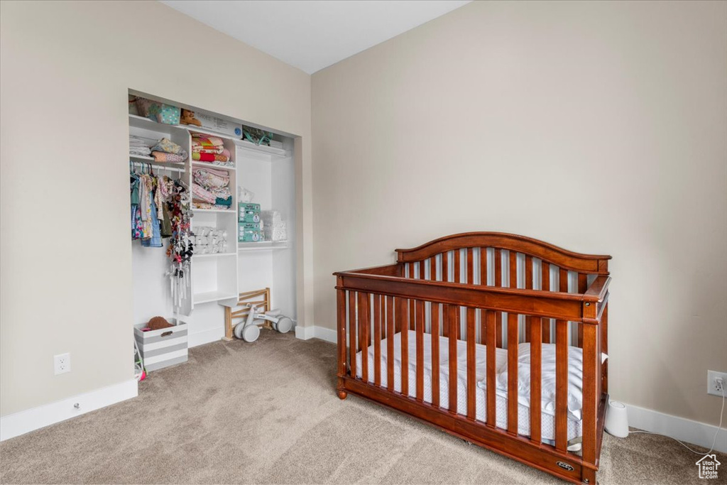 Bedroom featuring carpet flooring and a crib