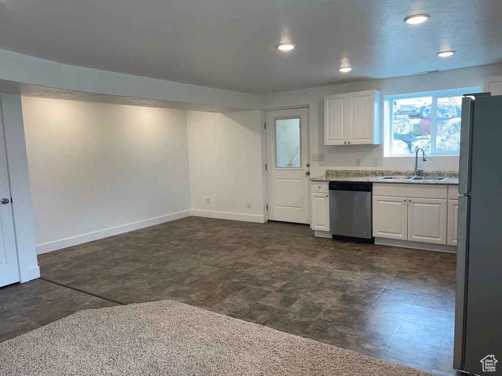 Kitchen with freestanding refrigerator, white cabinetry, dishwasher, recessed lighting, and light stone countertops