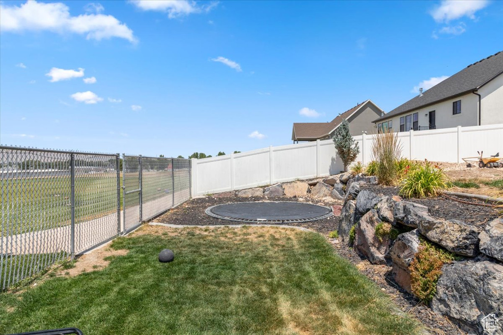 Fenced backyard featuring a trampoline