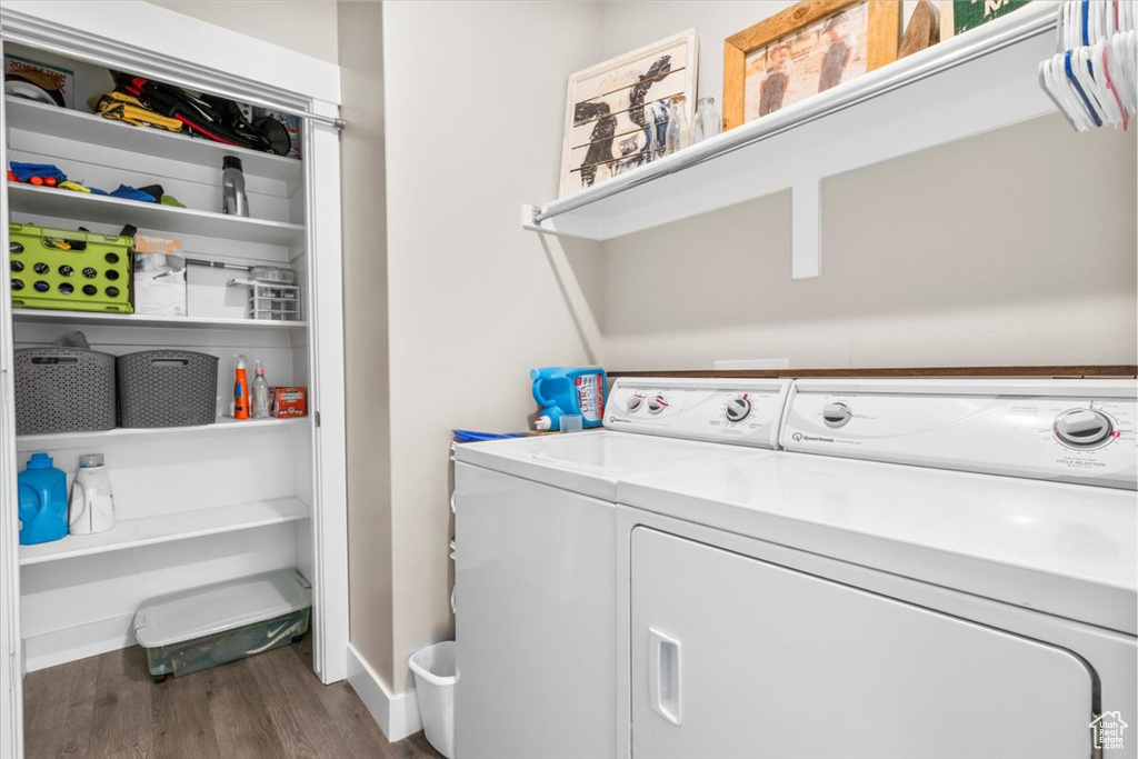 Laundry area with separate washer and dryer and wood finished floors