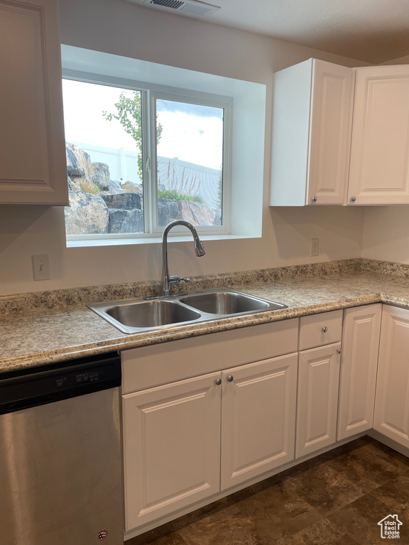 Kitchen featuring stainless steel dishwasher, white cabinets, and light countertops