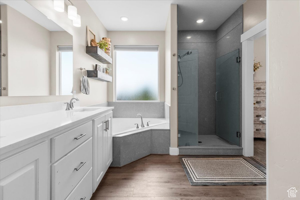 Full bath with a shower stall, vanity, a garden tub, and wood finished floors