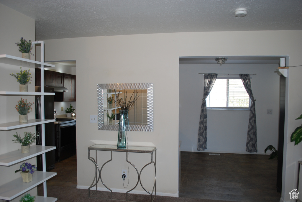 Foyer with a textured ceiling and dark colored carpet