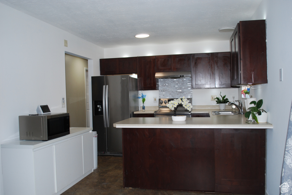 Kitchen with stainless steel appliances, light countertops, a peninsula, and dark brown cabinetry