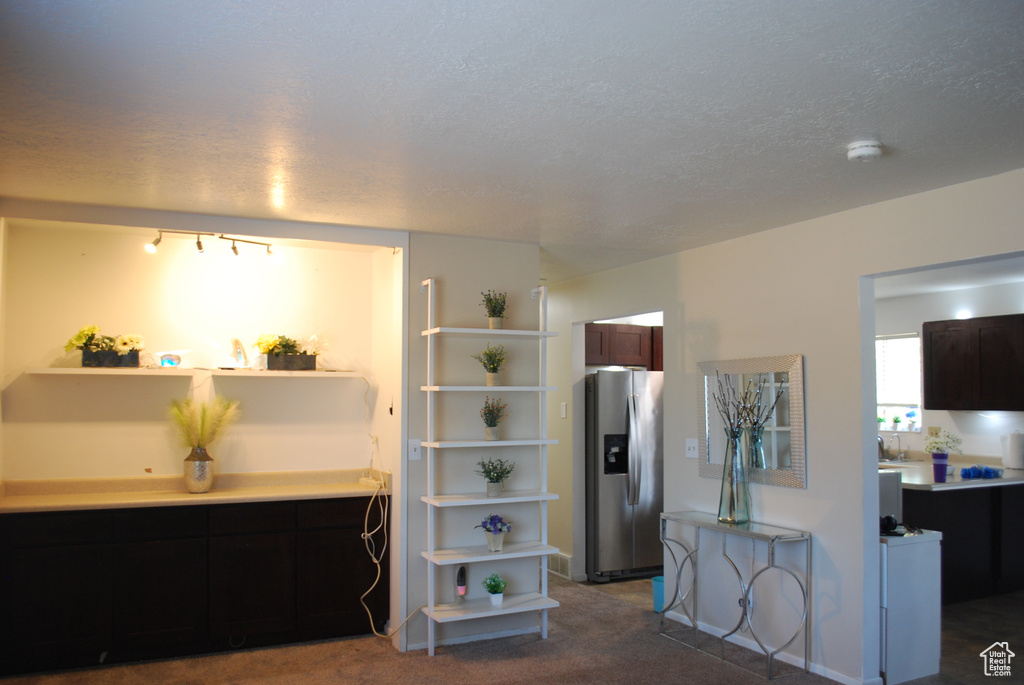 Kitchen with open shelves, stainless steel refrigerator with ice dispenser, carpet floors, light countertops, and a textured ceiling