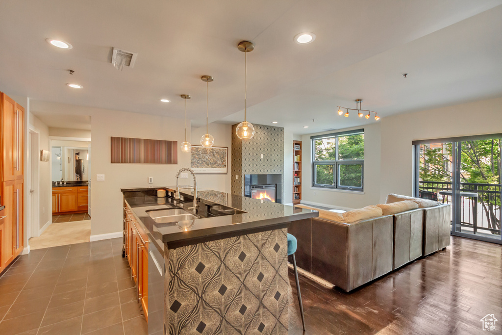 Kitchen featuring dark countertops, open floor plan, recessed lighting, a glass covered fireplace, and a breakfast bar