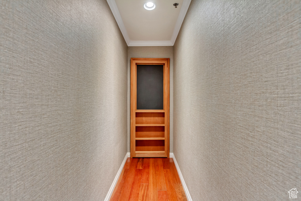 Corridor with light wood-style flooring, ornamental molding, recessed lighting, and a textured wall