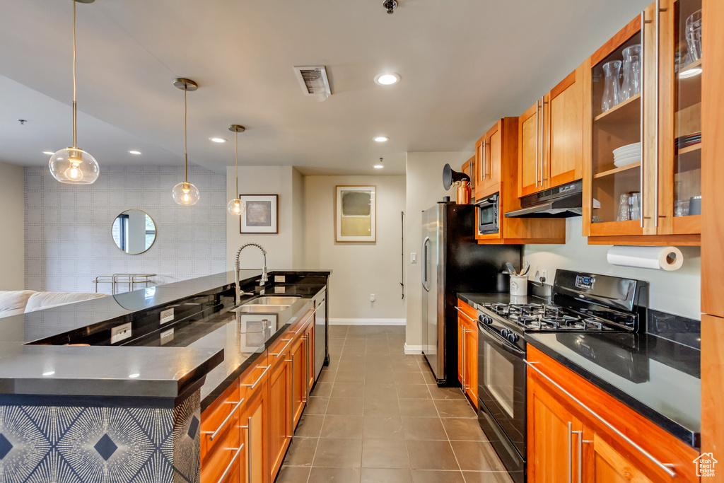 Kitchen with appliances with stainless steel finishes, dark countertops, brown cabinetry, and recessed lighting