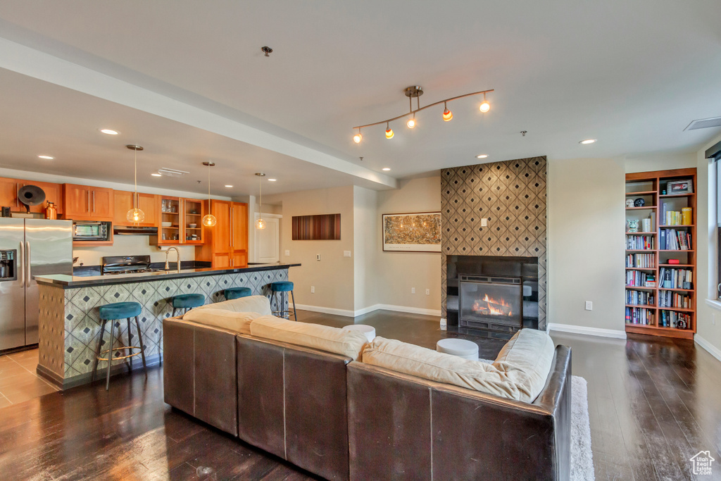 Living room with dark wood-style floors, a fireplace, and recessed lighting