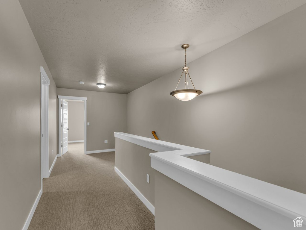 Corridor featuring an upstairs landing, carpet, and a textured ceiling