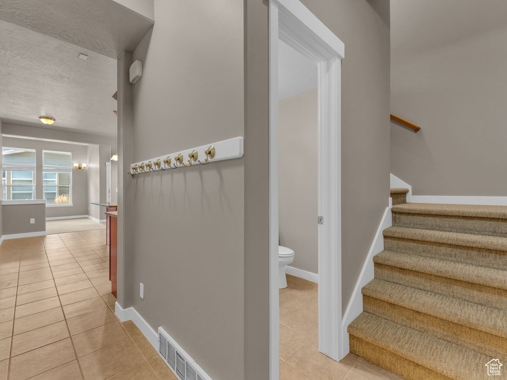 Stairs with tile patterned flooring and a textured ceiling