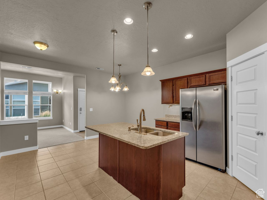 Kitchen featuring stainless steel fridge, recessed lighting, light stone countertops, light tile patterned floors, and decorative light fixtures