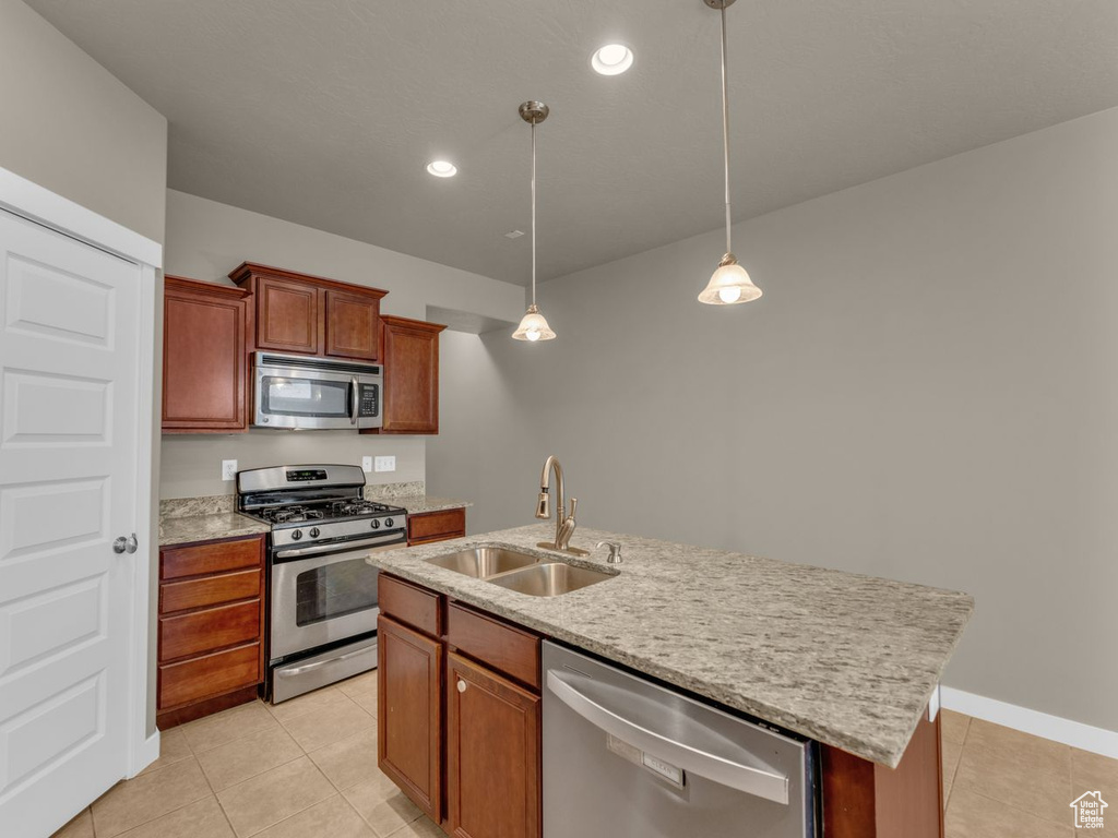 Kitchen with stainless steel appliances, light tile patterned floors, pendant lighting, a center island with sink, and recessed lighting