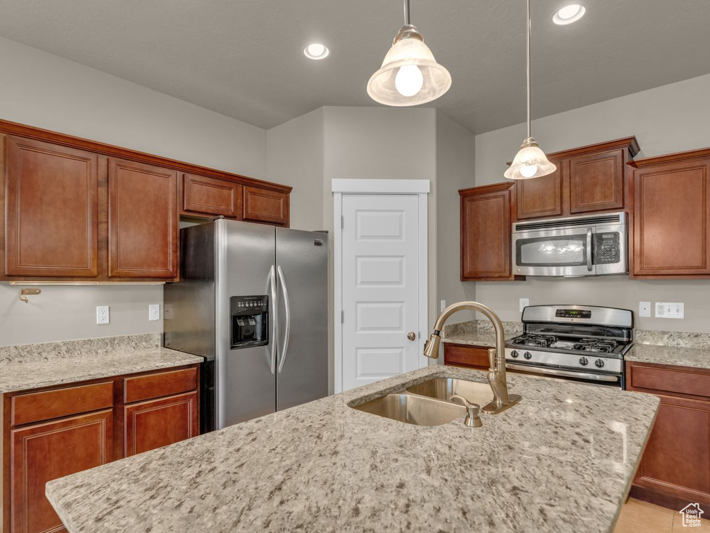 Kitchen with appliances with stainless steel finishes, hanging light fixtures, light stone counters, recessed lighting, and brown cabinetry