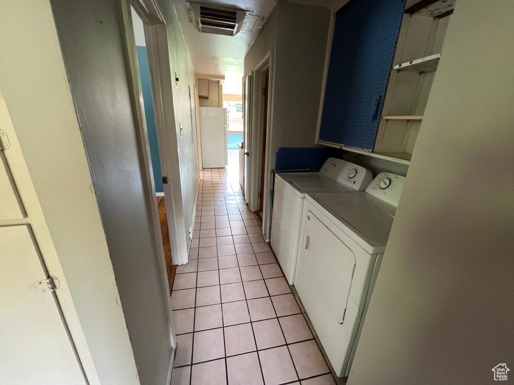 Laundry room with washer and clothes dryer and light tile patterned floors