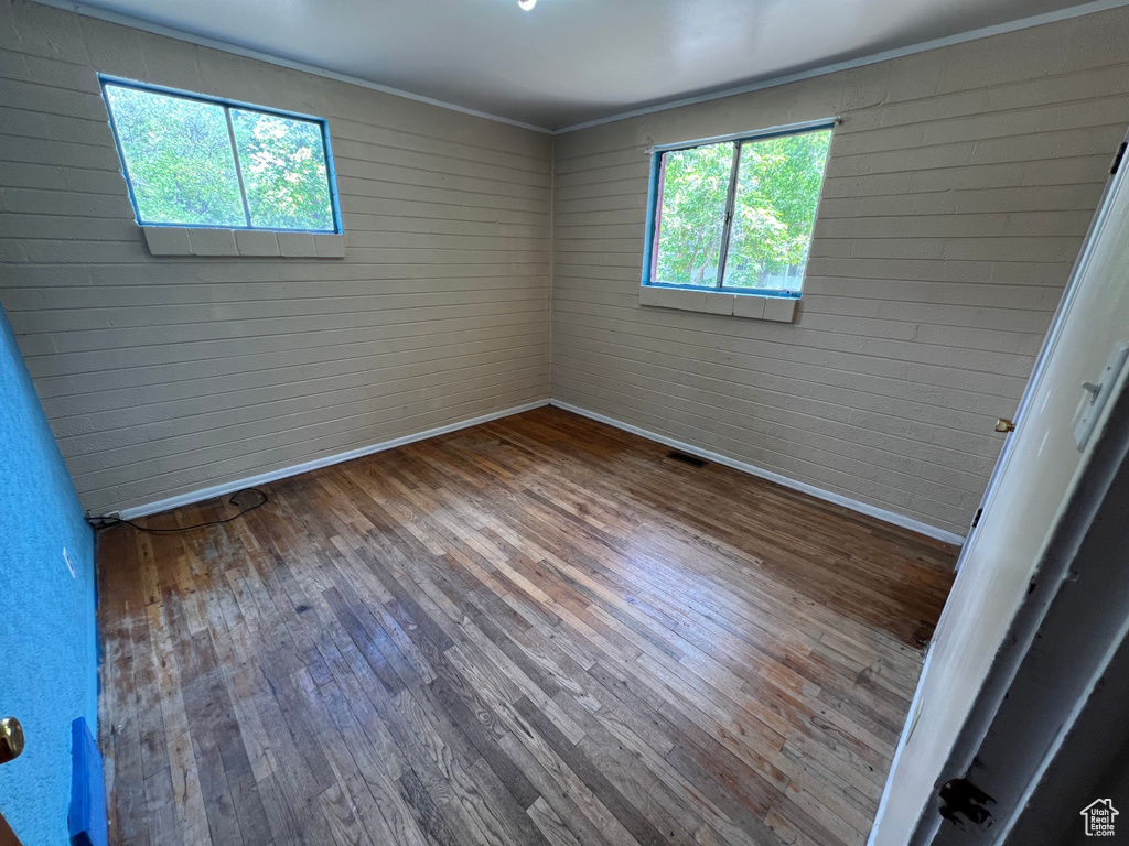 Unfurnished room featuring healthy amount of natural light, wood-type flooring, and ornamental molding