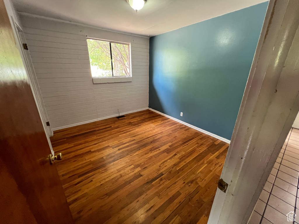 Unfurnished room featuring hardwood / wood-style floors and wooden walls