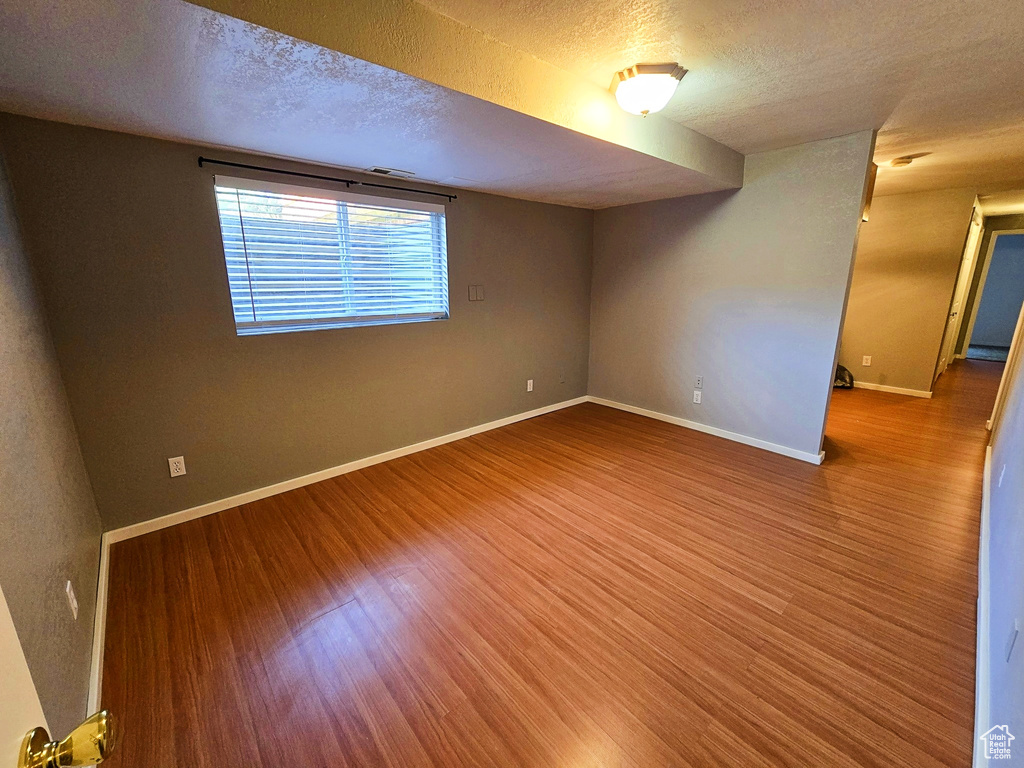 Spare room with wood finished floors and a textured ceiling