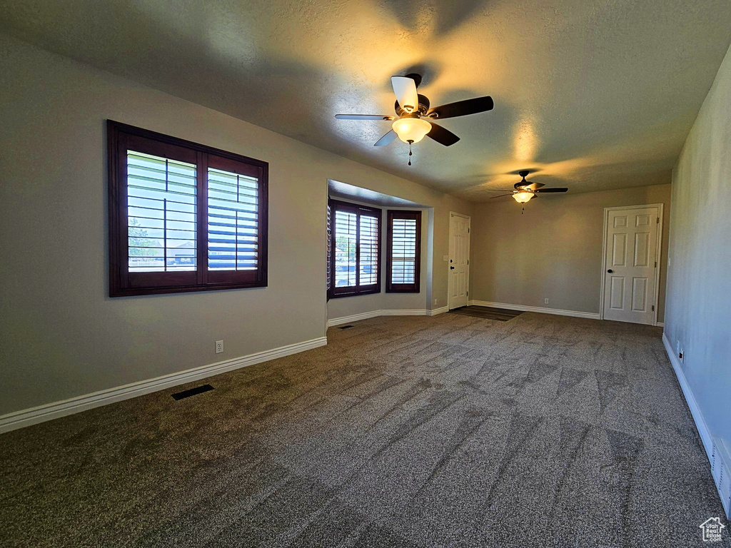 Unfurnished room with ceiling fan, carpet, and a textured ceiling