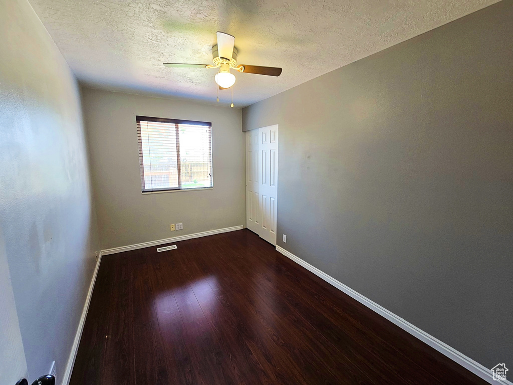 Empty room featuring wood finished floors, a textured ceiling, and a ceiling fan