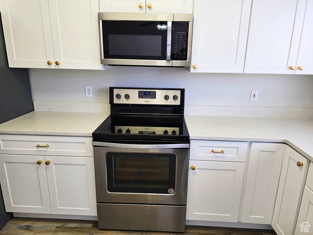 Kitchen with stainless steel appliances, white cabinets, and light countertops
