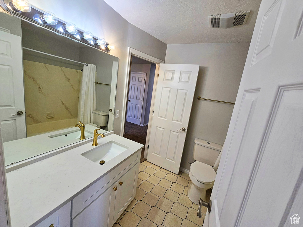 Bathroom with vanity, a shower with shower curtain, a textured ceiling, and tile patterned floors