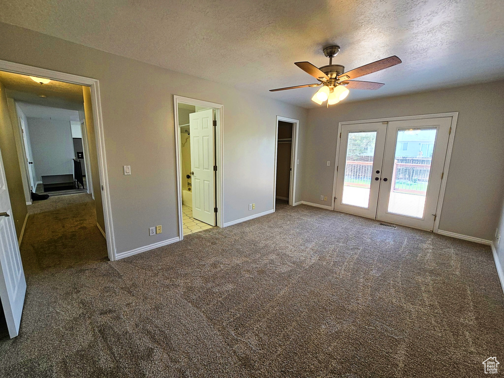 Unfurnished bedroom featuring french doors, access to outside, carpet floors, a textured ceiling, and ensuite bathroom