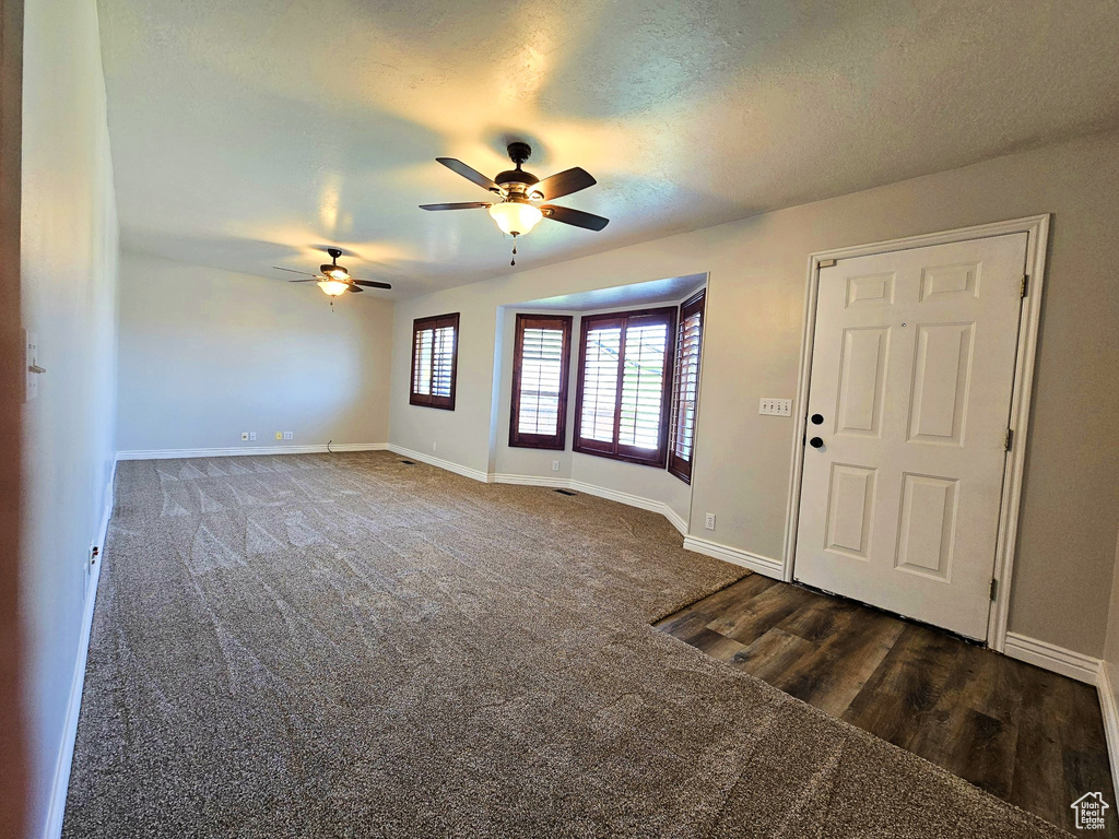 Entryway with a ceiling fan, dark wood finished floors, and dark colored carpet