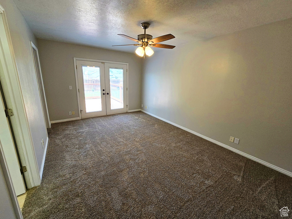 Carpeted spare room featuring french doors, a textured ceiling, and ceiling fan