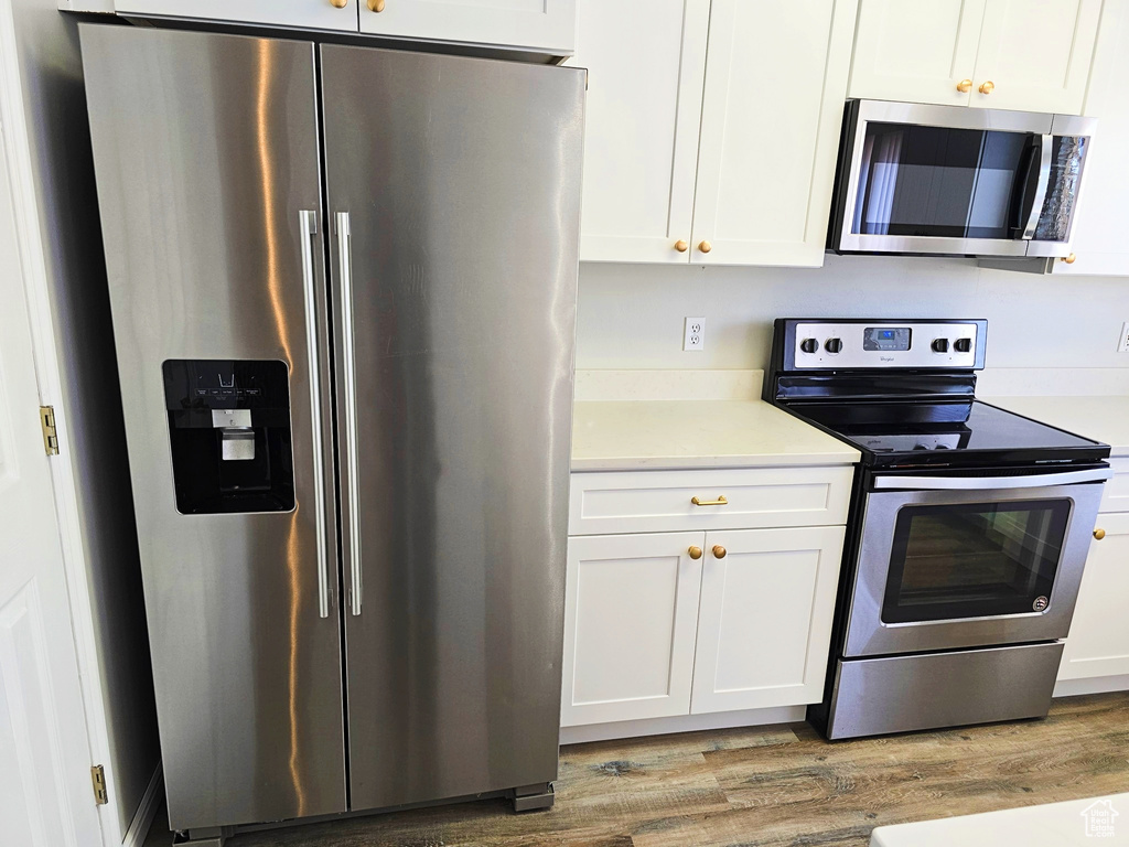 Kitchen featuring stainless steel appliances, light wood-style floors, light countertops, and white cabinetry