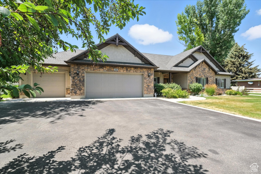 Craftsman-style house with stone siding, a garage, driveway, and stucco siding