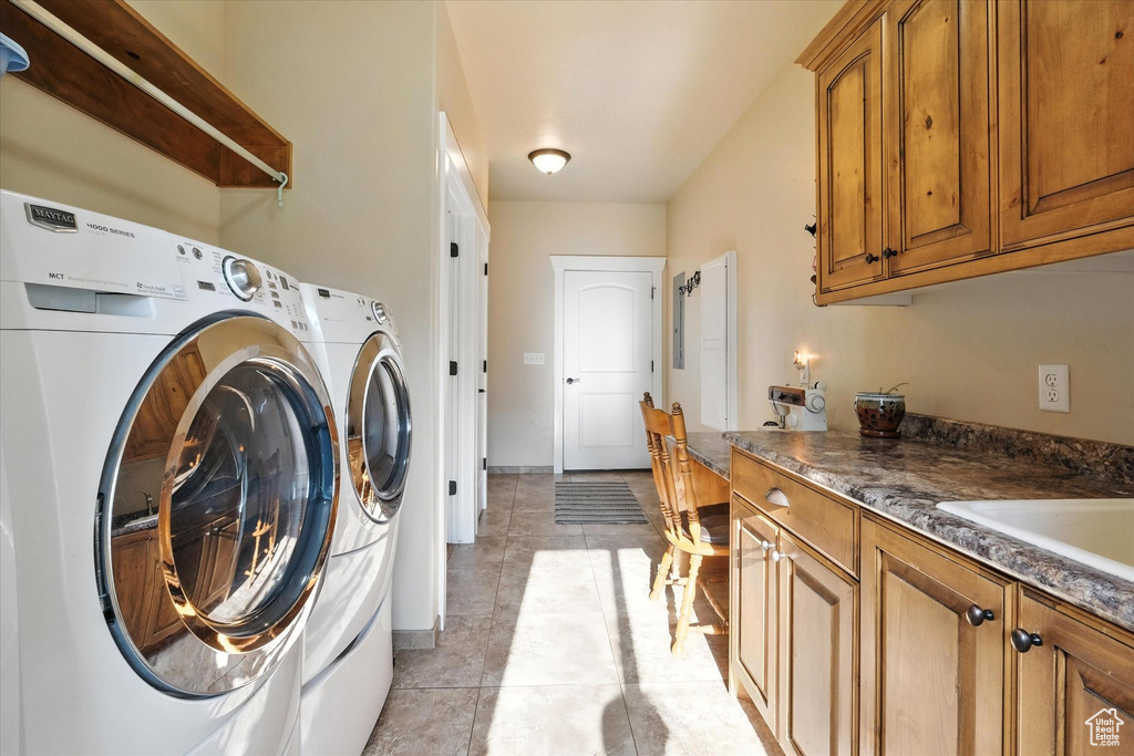 Laundry room with washing machine and dryer, light tile patterned flooring, and cabinet space