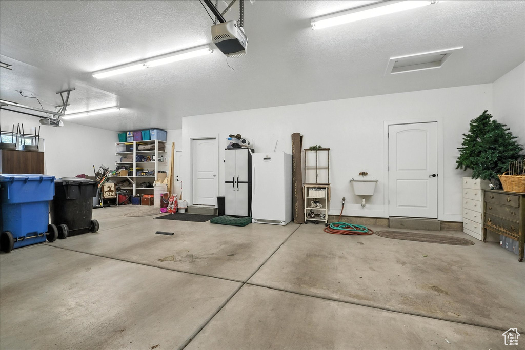Garage featuring freestanding refrigerator and a garage door opener