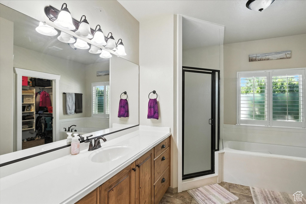 Full bath with a bath, a stall shower, a walk in closet, and vanity