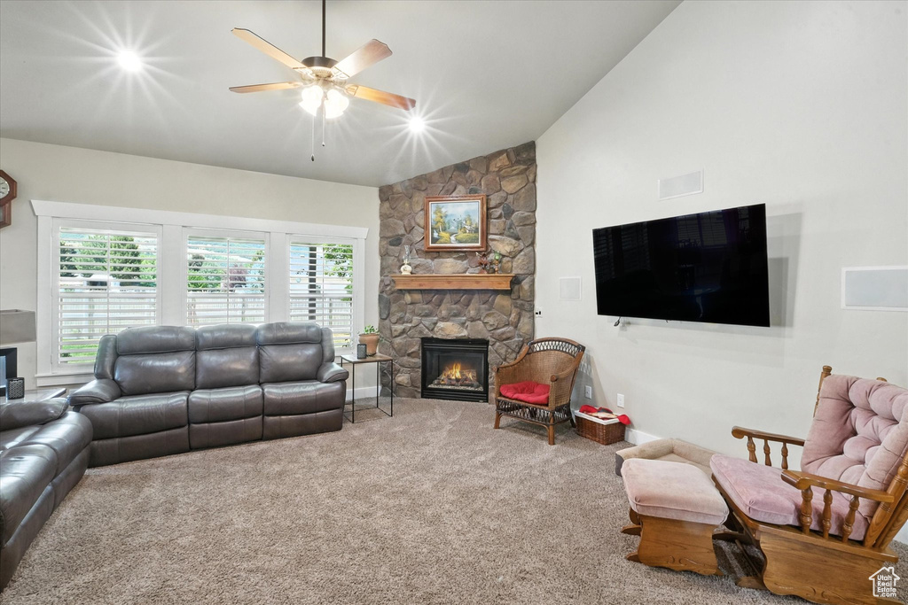 Living area featuring a fireplace, a ceiling fan, carpet flooring, and high vaulted ceiling