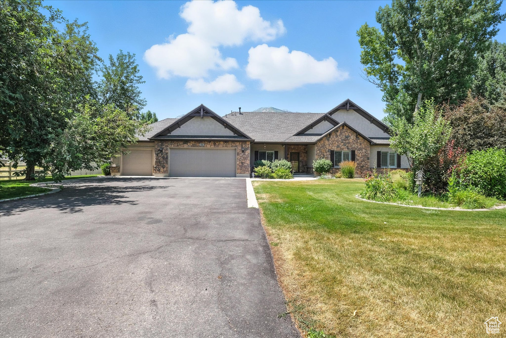 Craftsman house with stone siding, driveway, an attached garage, and a front yard