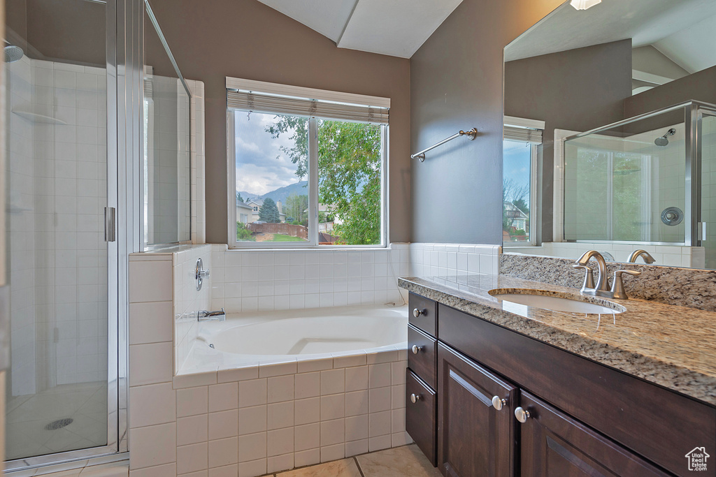 Bathroom featuring lofted ceiling, vanity, a shower stall, a bath, and tile patterned floors