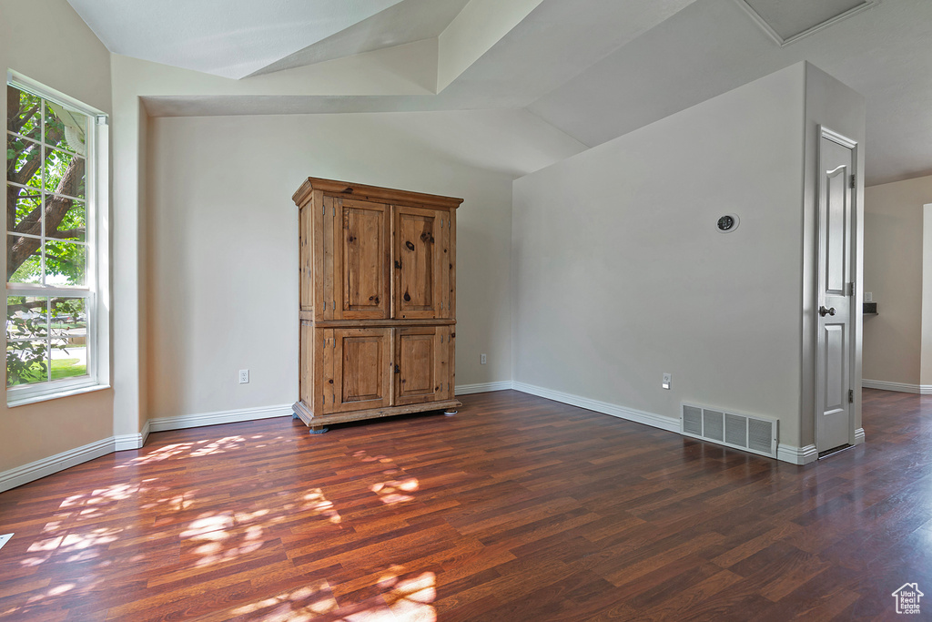 Spare room with lofted ceiling and dark wood-style flooring