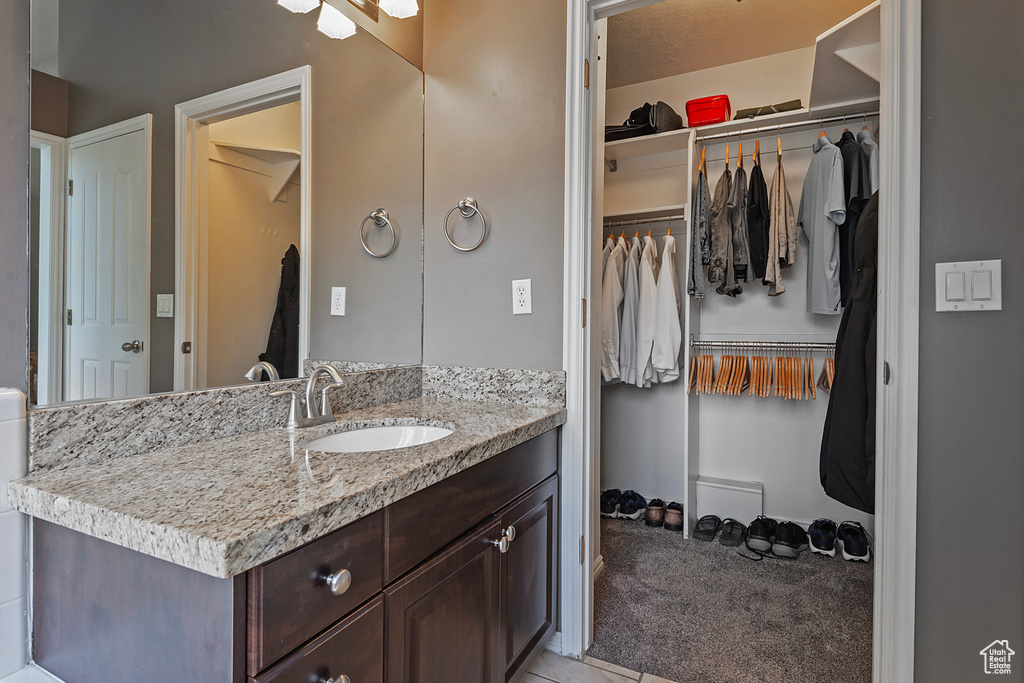 Bathroom with vanity, a spacious closet, and tile patterned floors